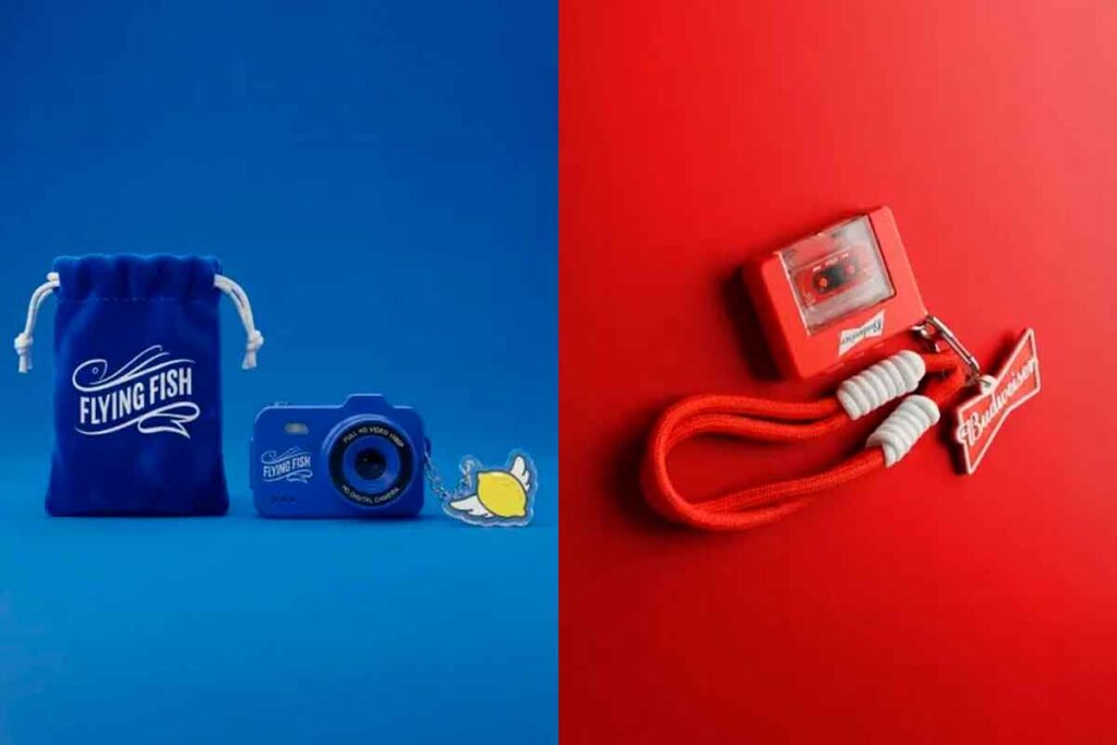 Estandes das marcas Flying Fish e Budweiser apresentando brindes tecnológicos e retrô, como minicâmeras e gravadores, em evento de inovação.